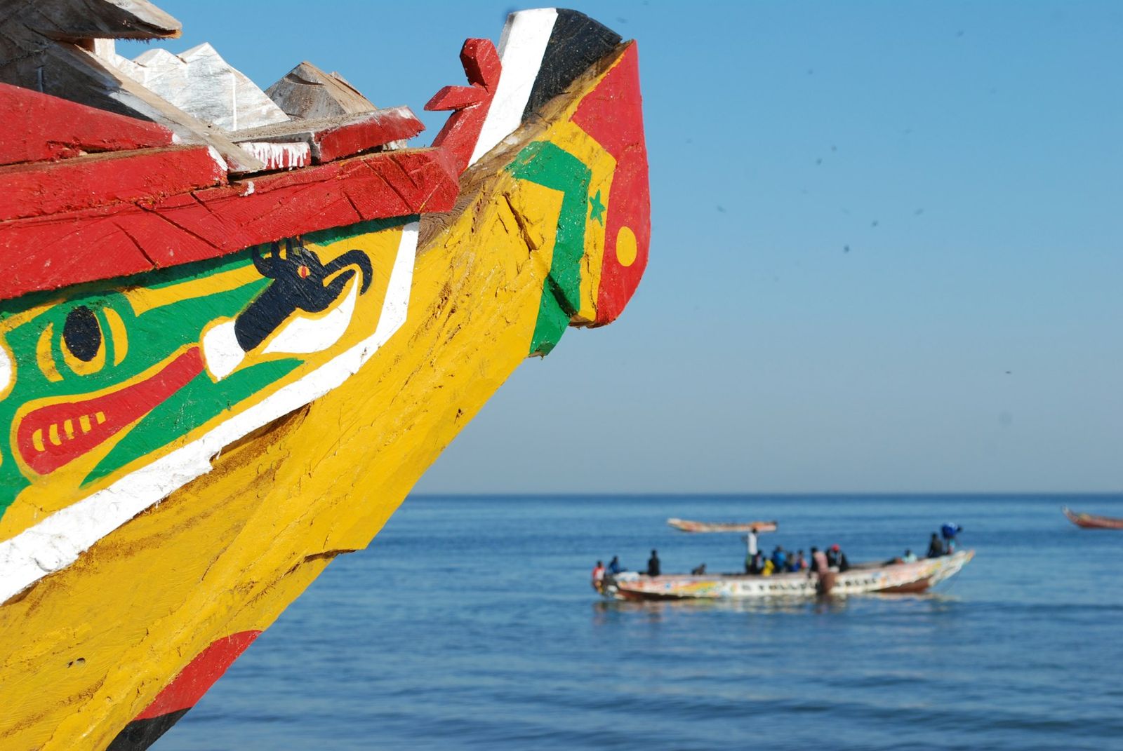 Proue d’une pirogue peinte, pêcheurs au large